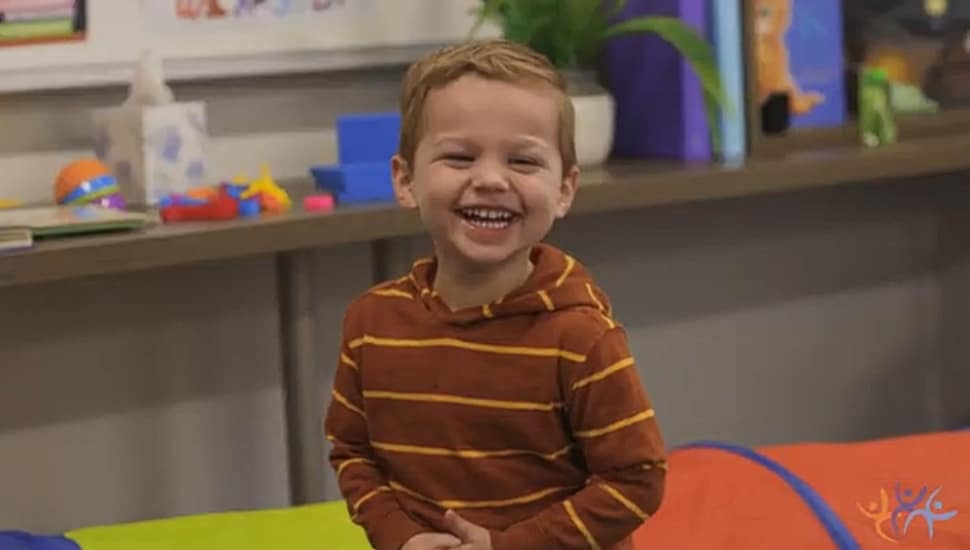 A little boy offers up a big smile in the classroom.