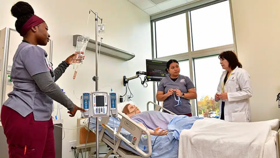 Student nurses care for mannequin patient.
