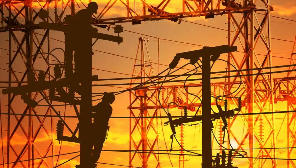 Power linemen work late on electric power supply station.