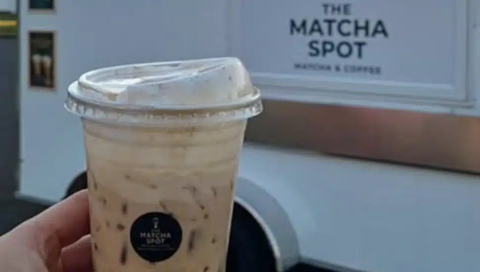 A hand holds up a matcha beverage in front of The Matcha Spot in Hatboro.