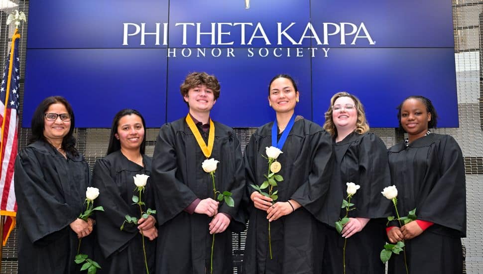 Phi Theta Kappa honor society members at Montgomery County Community College holding white roses during an induction ceremony