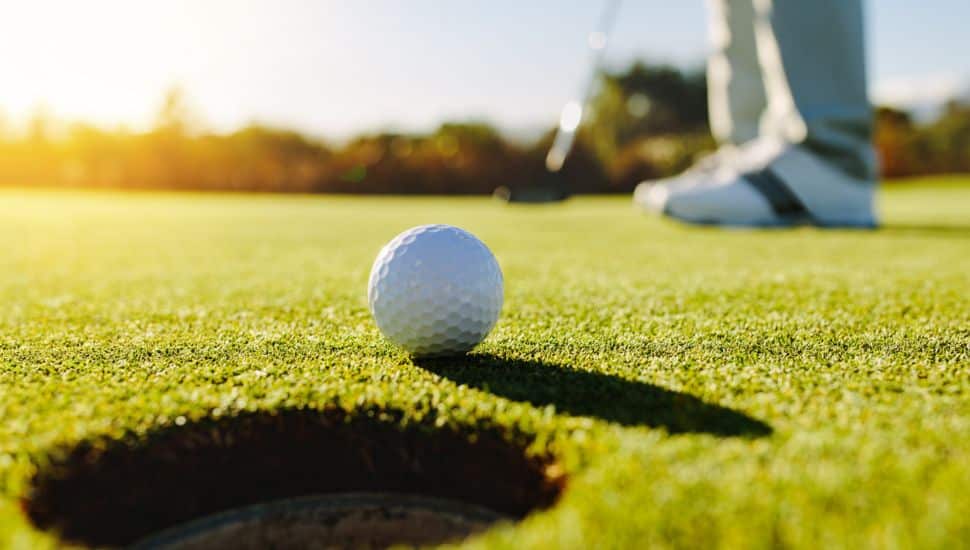 A golfer puts a ball into the hole.