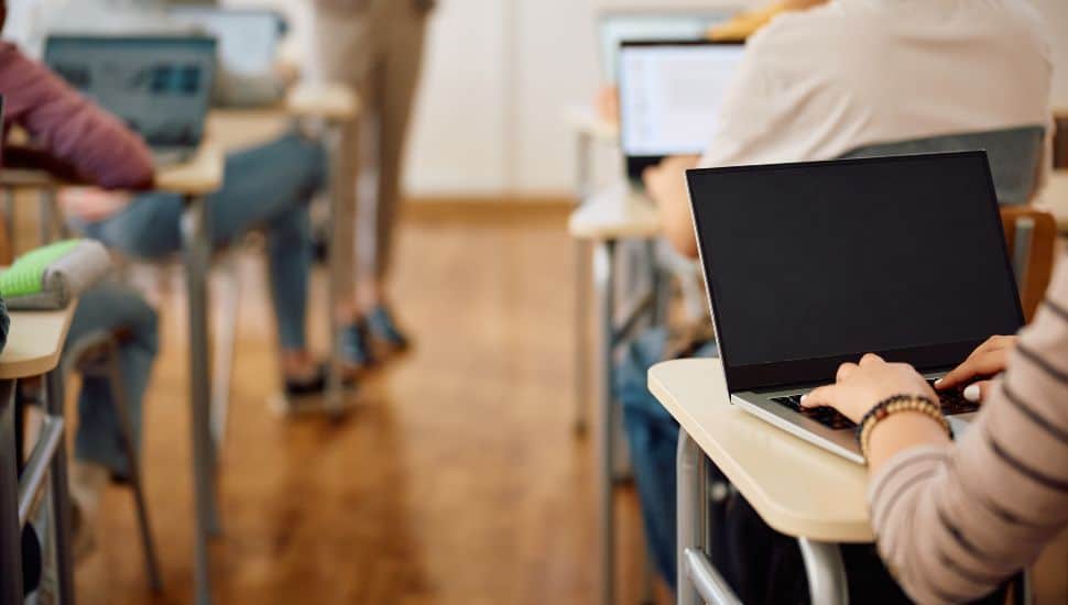 Close up of female student e-learning on a computer during a class at high school.