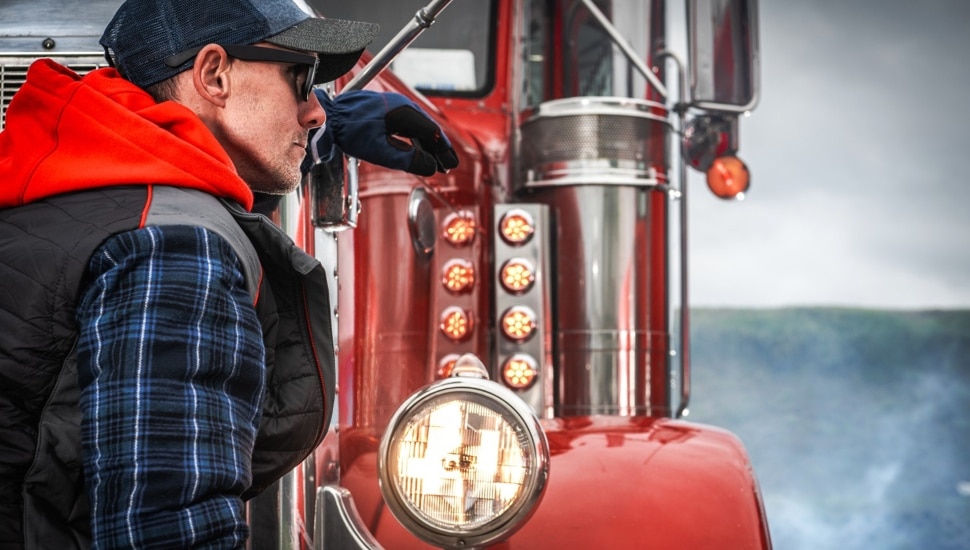 Professional Truck Driver Leans Against Vintage Truck.