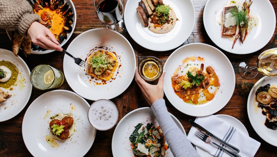 Friends celebrate over a vibrant restaurant dining table.