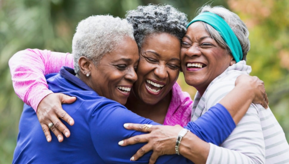 A group of three seniors embrace.