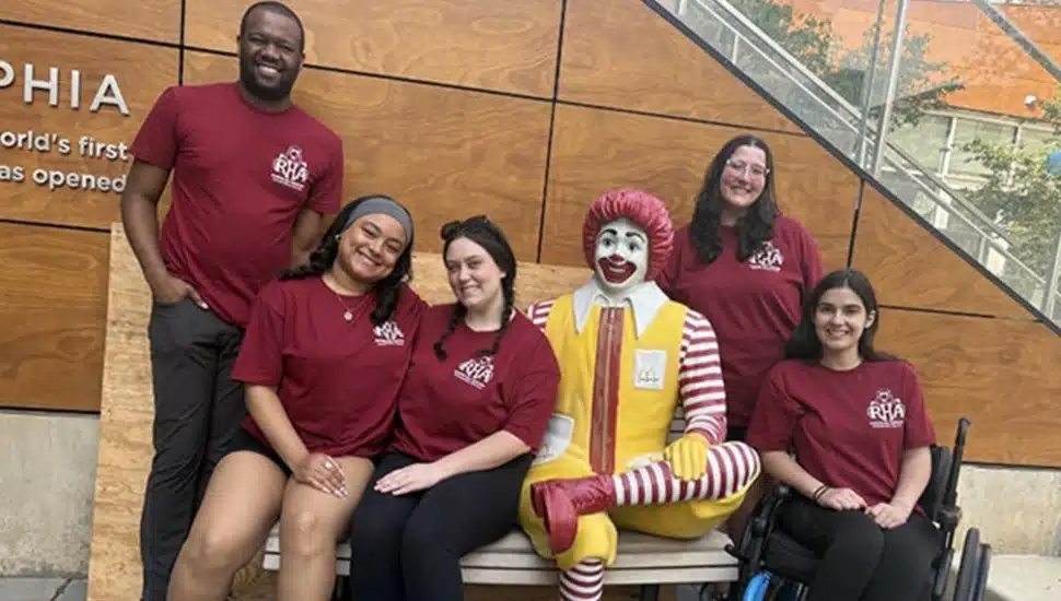 College students pose for picture with Ronald McDonald statue.