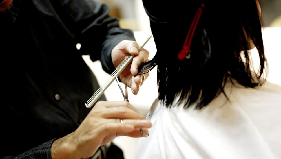 Cosmetologist cuts woman's hair.