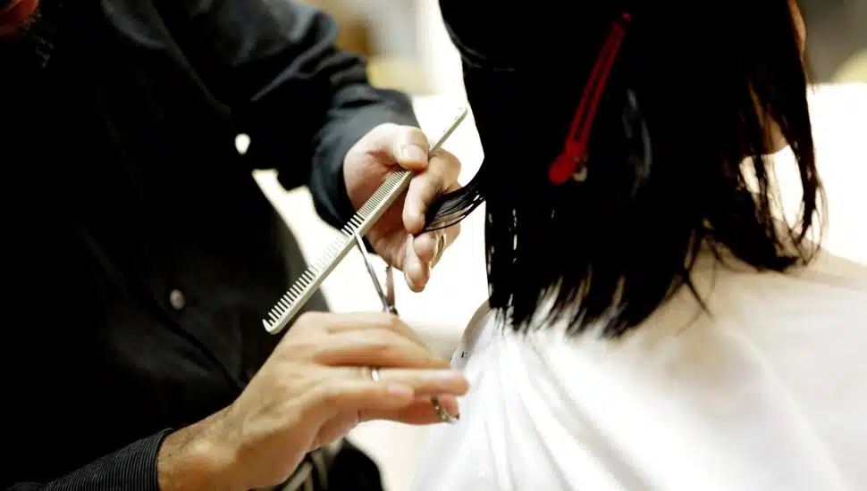 Cosmetologist cuts woman's hair.
