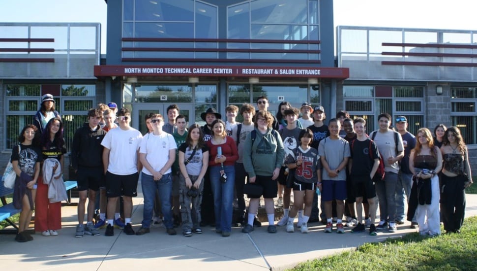 High school students pose for group picture in front of school.