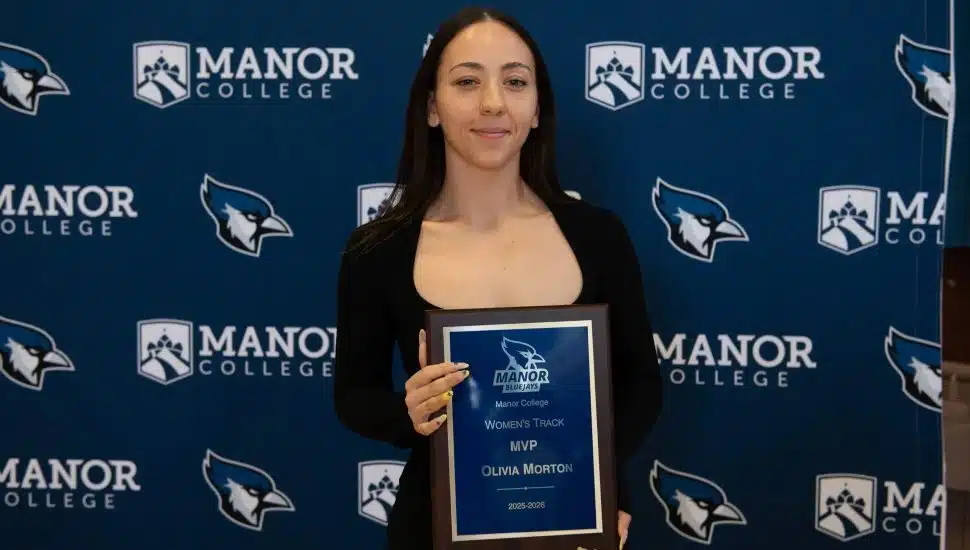 Olivia Morton holds her Manor College Women's Track MVP award plaque at the 2025-2026 Student Athlete Awards Dinner.