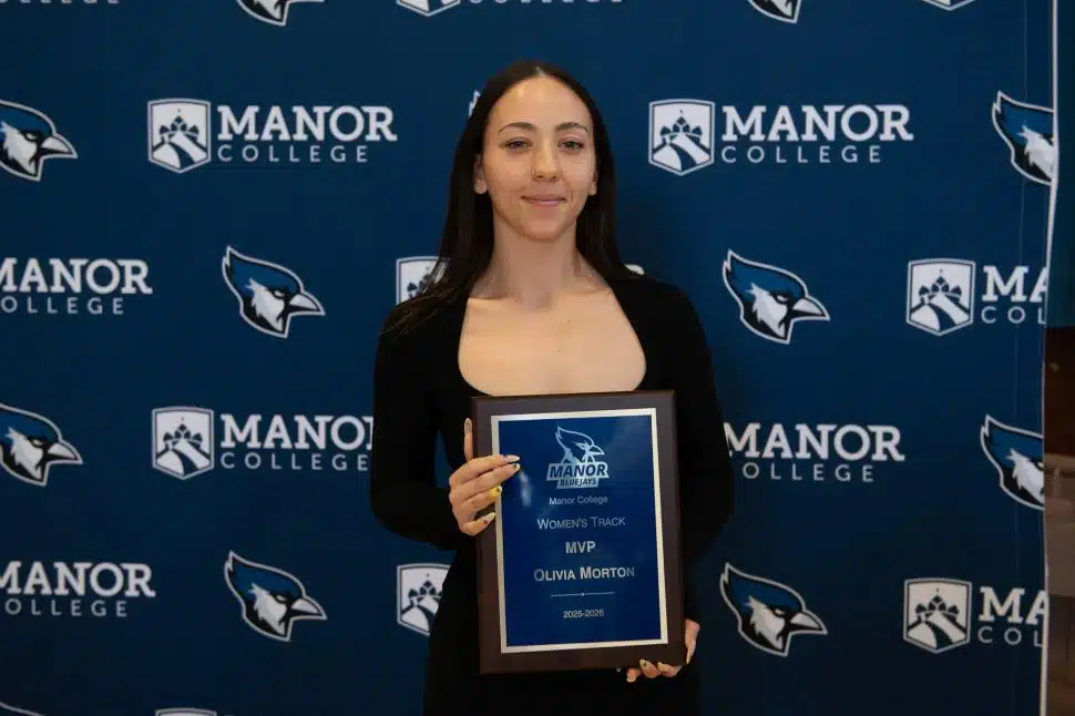 Olivia Morton holds her Manor College Women's Track MVP award plaque at the 2025-2026 Student Athlete Awards Dinner.