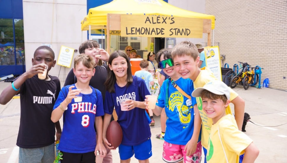 A group of happy children smile in front of an Alex's Lemonade Stan