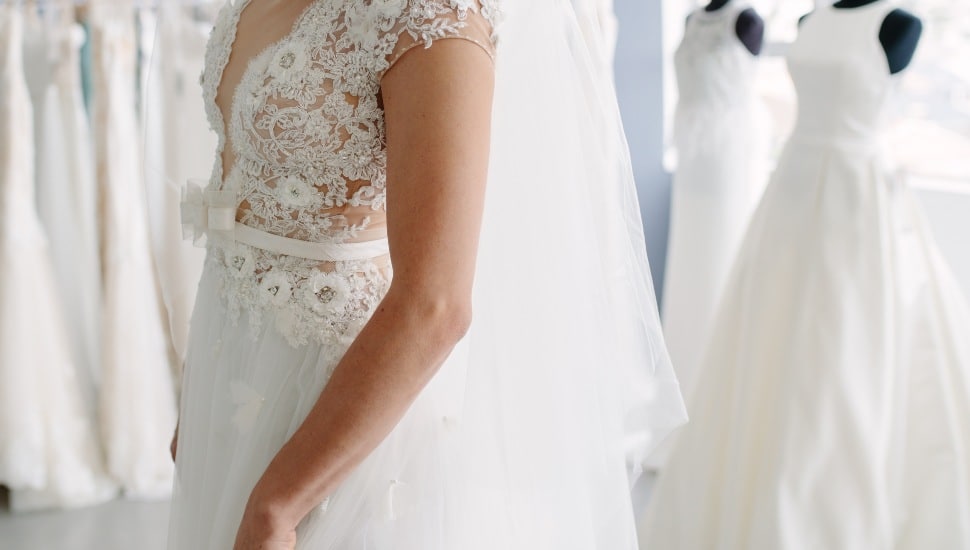 A soon-to-be bride tries on a wedding dress in a fitting room.
