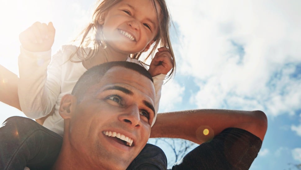 A man holds his daughter on his shoulders.