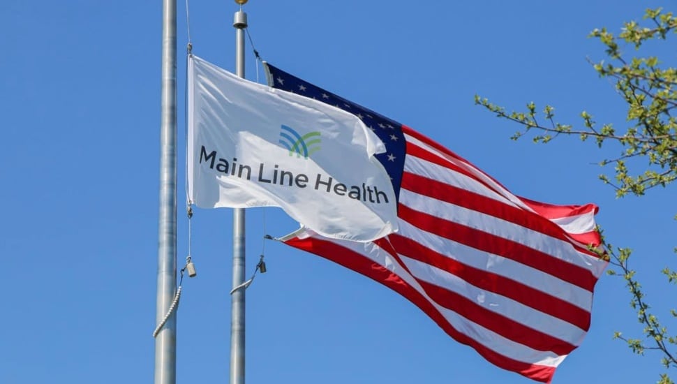 The Main Line Health flag waves next to the American flag.
