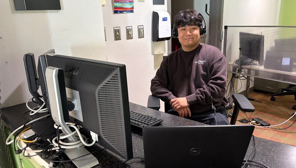 Joshua Jang behind computer desk, smiling.