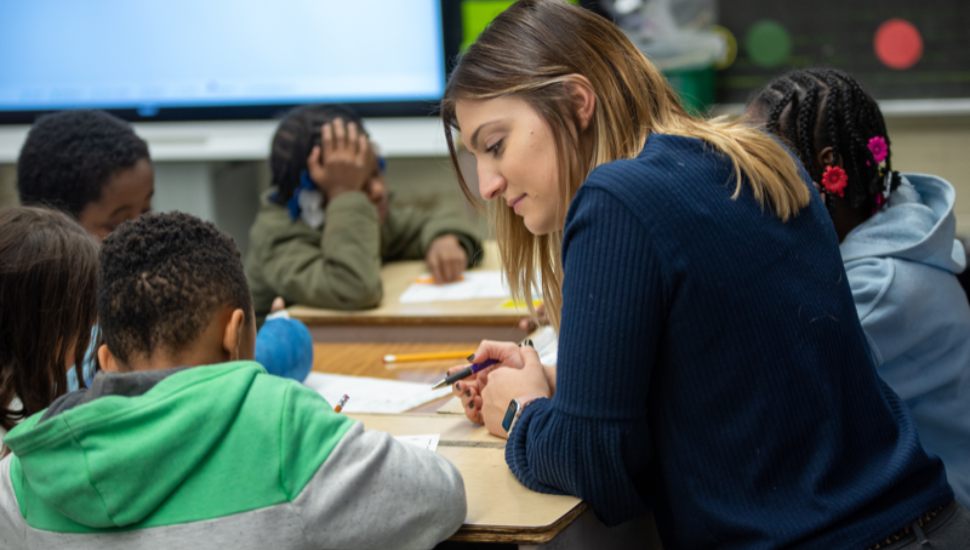 A future teacher works with elementary school students during a classroom lesson as part of West Chester University's PRIZE Program, which prepares aspiring educators through real-world teaching experiences.